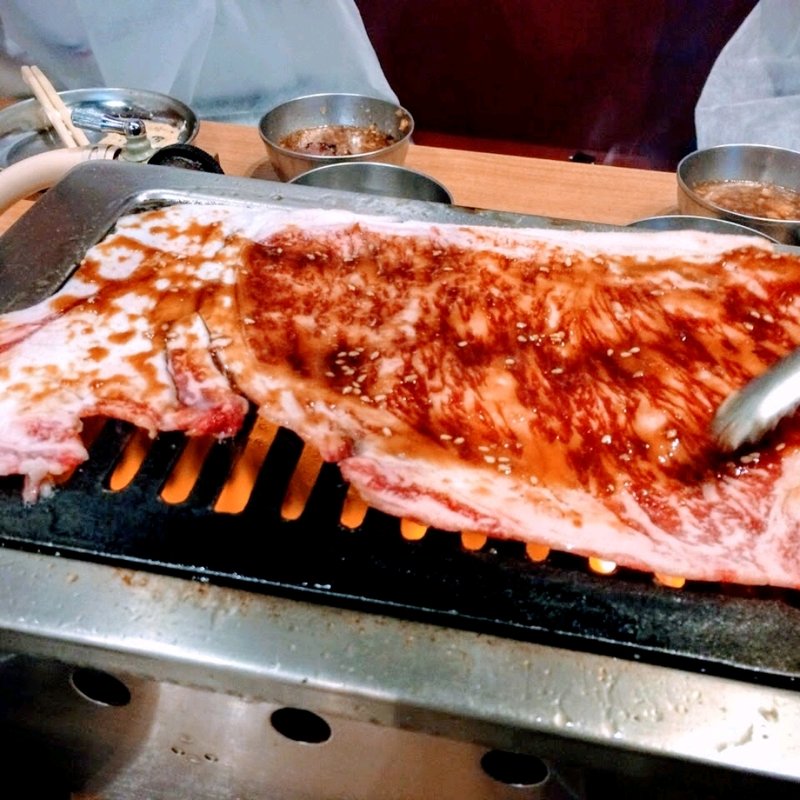 名物黒毛和牛のはみ出るカルビ(大阪焼肉・ホルモンふたご 中目黒本館)